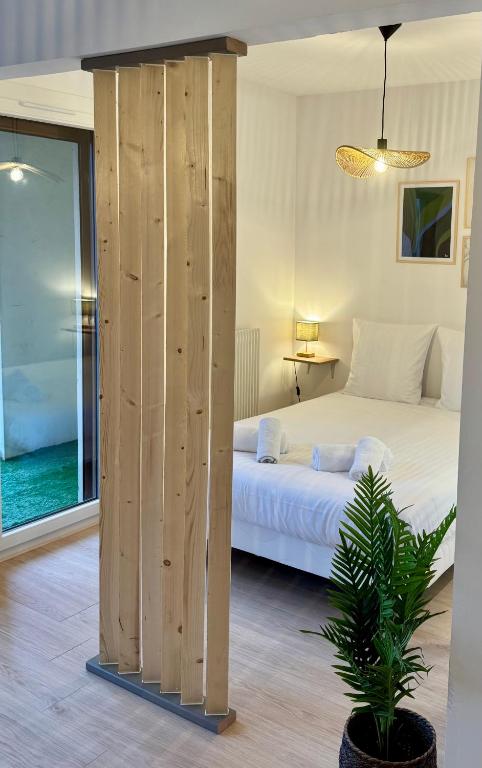 une chambre avec un lit blanc et une cloison en bois dans l'établissement Chaleureux studio entre lac et montagnes, à Neuvecelle