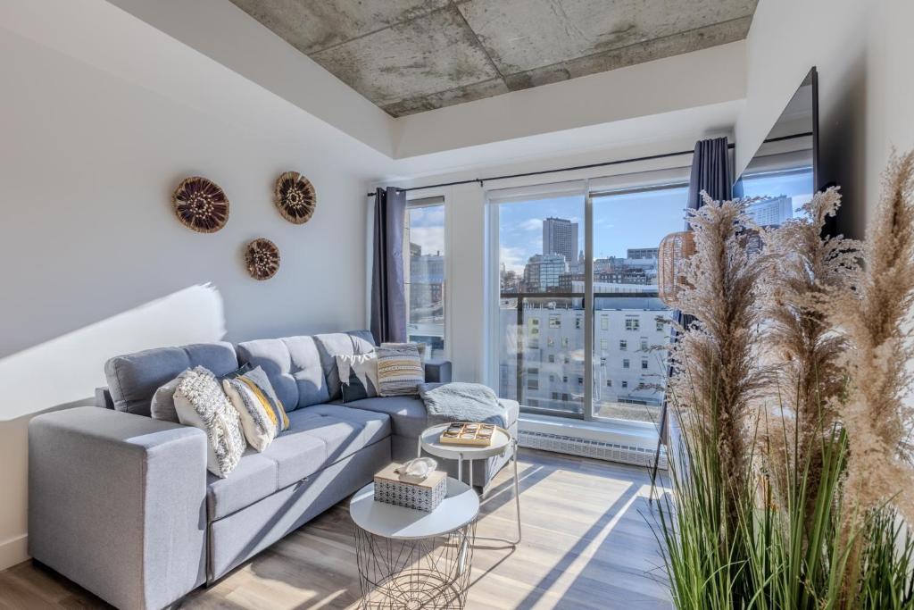 ein Wohnzimmer mit Couch und großem Fenster in der Unterkunft L'Horizon Urbain, Centre Ville, Toit-Terrasse Gym in Québec