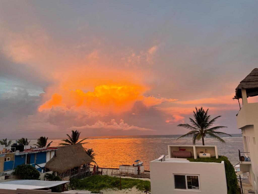 een zonsondergang over de oceaan met huizen en palmbomen bij Casa Velero Puerto Morelos in Puerto Morelos