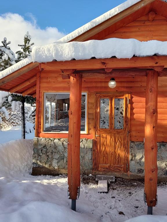 a wooden cabin with snow on the roof at Entre Cerros Tiny House Única in Moquehue