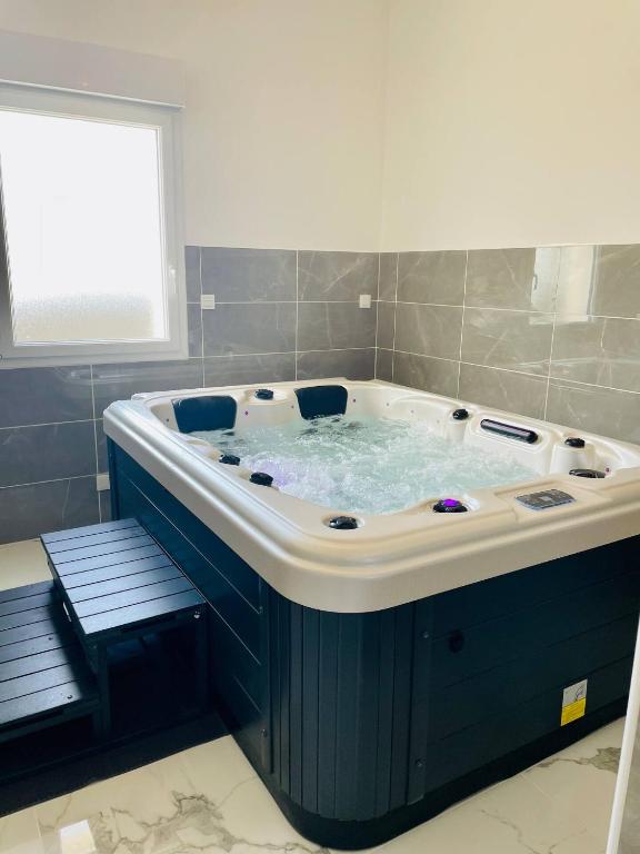 une grande baignoire dans une salle de bain avec une fenêtre dans l'établissement Jacuzzi privé 500m de la mer, à Blainville-sur-Mer