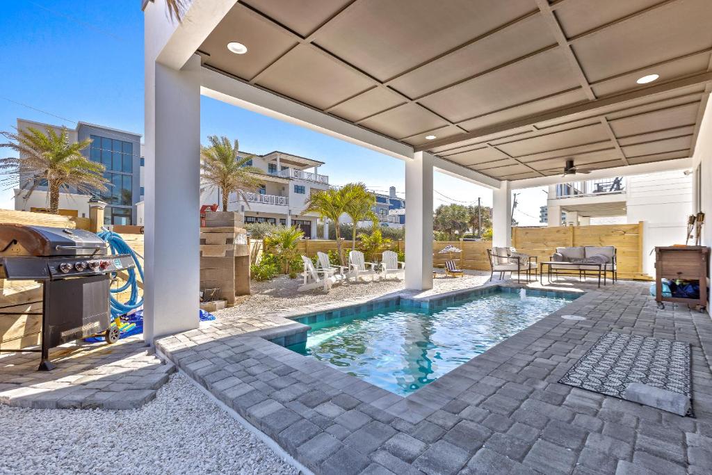a swimming pool with a patio and a grill at Sunrise Hideaway - Ocean View Luxury Pool Home - 350 Feet to the Beach in New Smyrna Beach