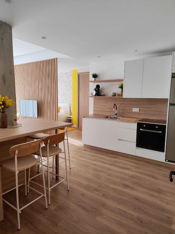 a kitchen with white cabinets and a table and chairs at Apartamento Mimosa Diseño Exclusivo in Ponteareas