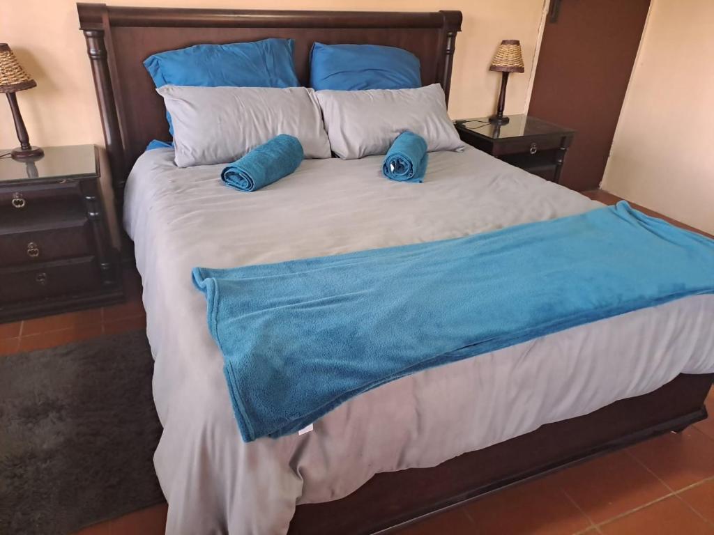 a bed with two blue pillows on top of it at Ithiliens Grace Guesthouse in Pretoria