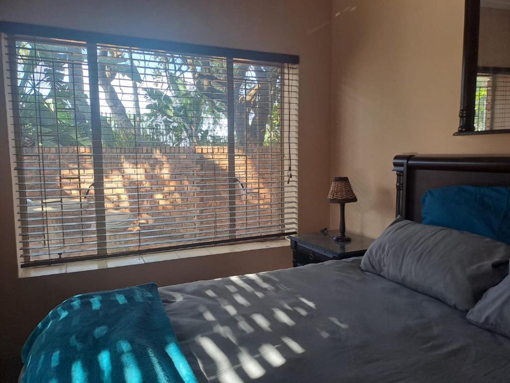 a bedroom with a bed and a window with a lion outside at Ithiliens Grace Guesthouse in Pretoria