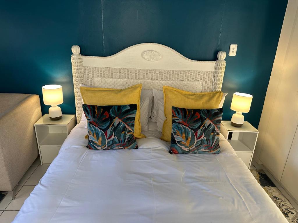 a bed with three pillows and two lamps on it at Private Cottage on Alamein in Cape Town