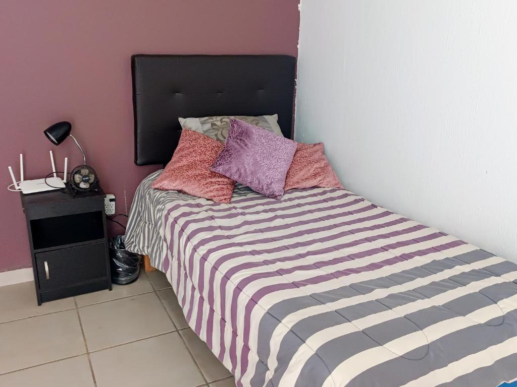 a bedroom with a bed with purple and purple pillows at Casa dentro de Coto Parques de Tesistan in Tesistán