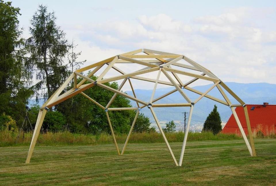 a large wooden structure in a grass field at Dom in Nowe Bystre
