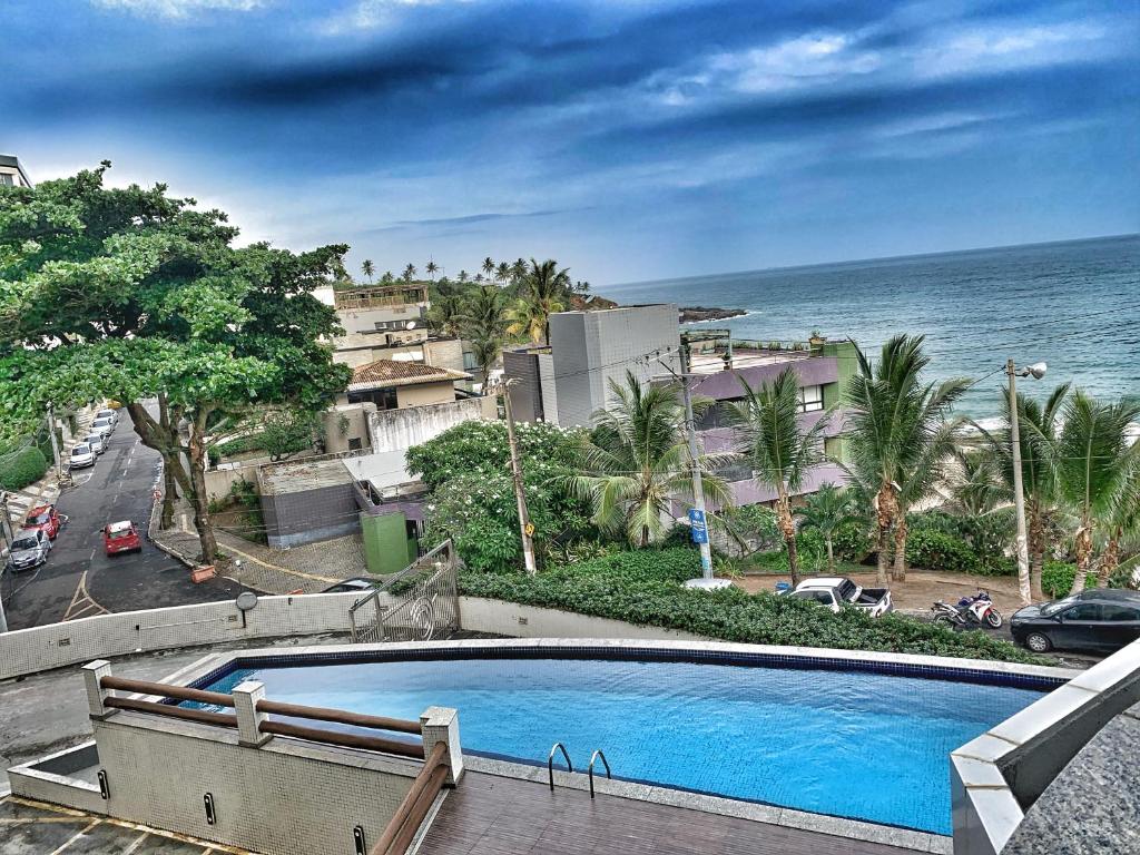 a swimming pool with the ocean in the background at Fabinhos SSA in Salvador