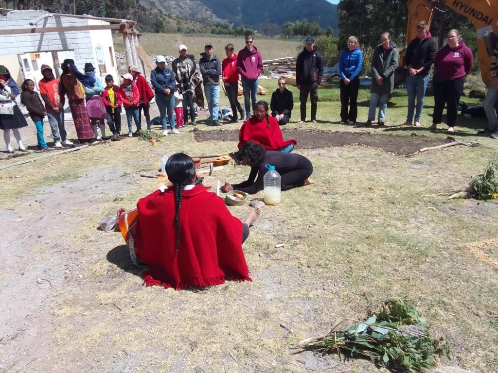 two women sitting on the ground with a crowd of people at Centro Turístico Comunitario Vivencial Guayama Grande in Sigchos