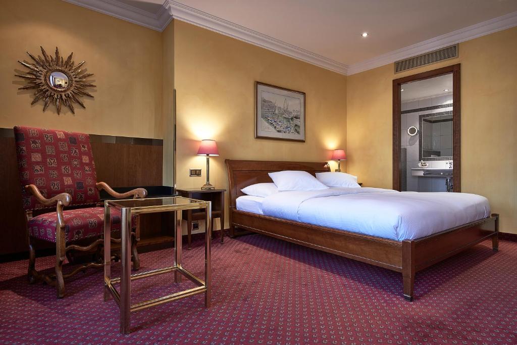 a hotel room with a bed and a desk and a chair at Hotel d'Allèves in Geneva