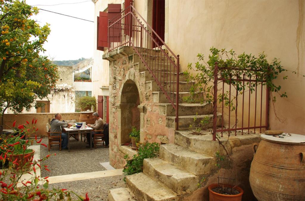 un patio al aire libre con escaleras y gente sentada en una mesa en Sior Nikoletos, en Vóroi