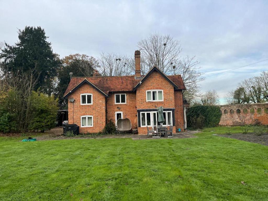 een groot bakstenen huis met een grote tuin bij Bucking Lodge in Wisley