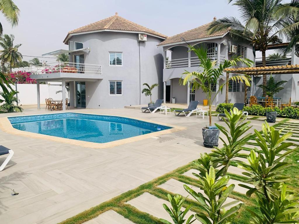 a villa with a swimming pool in front of a house at Villa Paco in Mbour