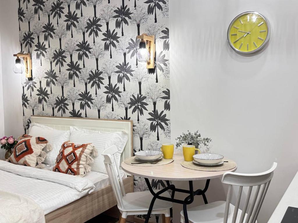 ein Schlafzimmer mit einem Bett und einem Tisch mit einer Uhr in der Unterkunft EmmaApart Comfort 11 in Astana