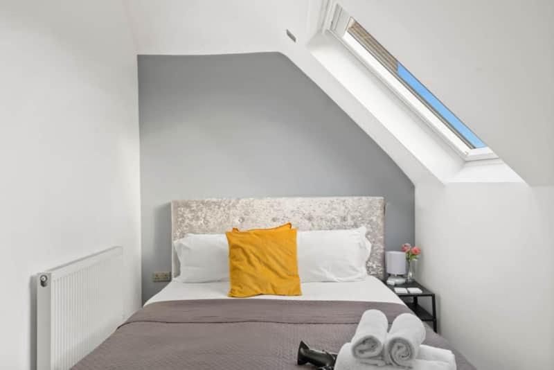 - une chambre dotée d'un lit avec des oreillers et des serviettes jaunes dans l'établissement BridgeCity Spacious 1 bed flat Maidstone Free Parking, à Maidstone