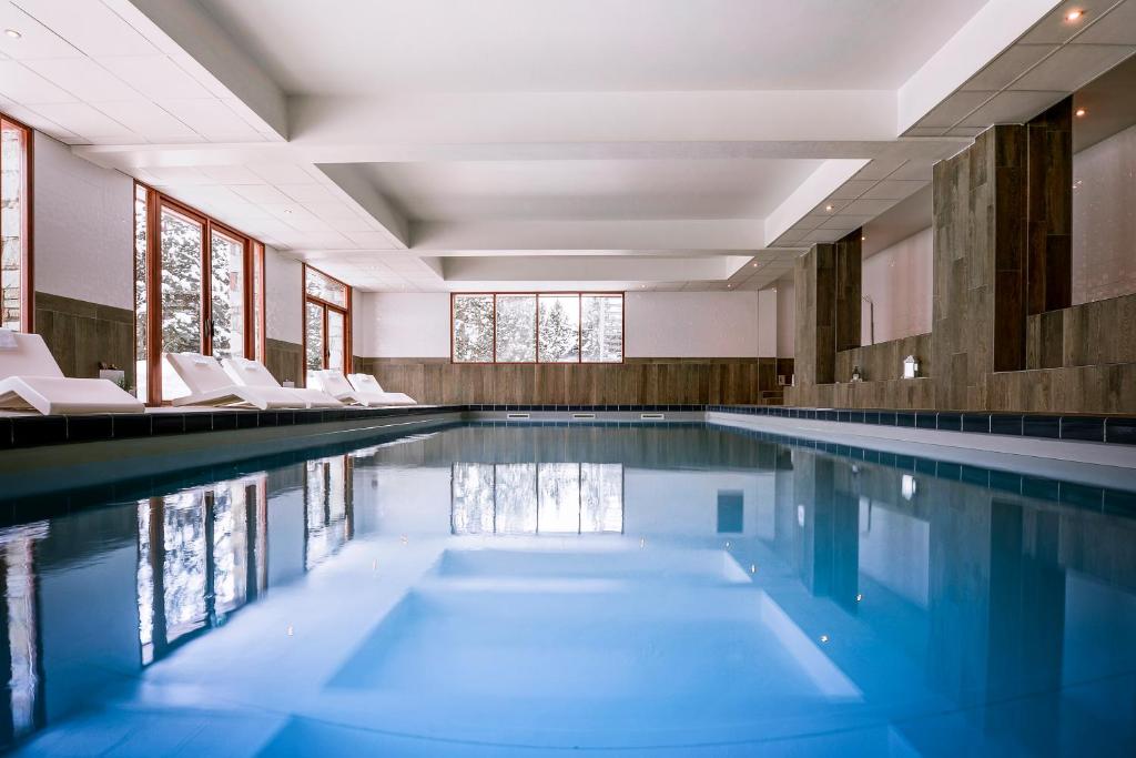 a swimming pool with white chairs in a building at Le Pic Blanc in L&#39;Alpe-d&#39;Huez