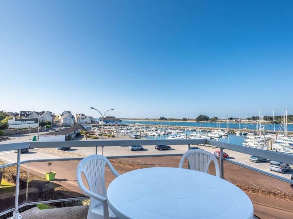 a table and chairs on a balcony overlooking a marina at Étel - Duplex 3 pièces - 42 m² - Piscine - Wifi - Animaux admis - FR-1-479-200 in Étel