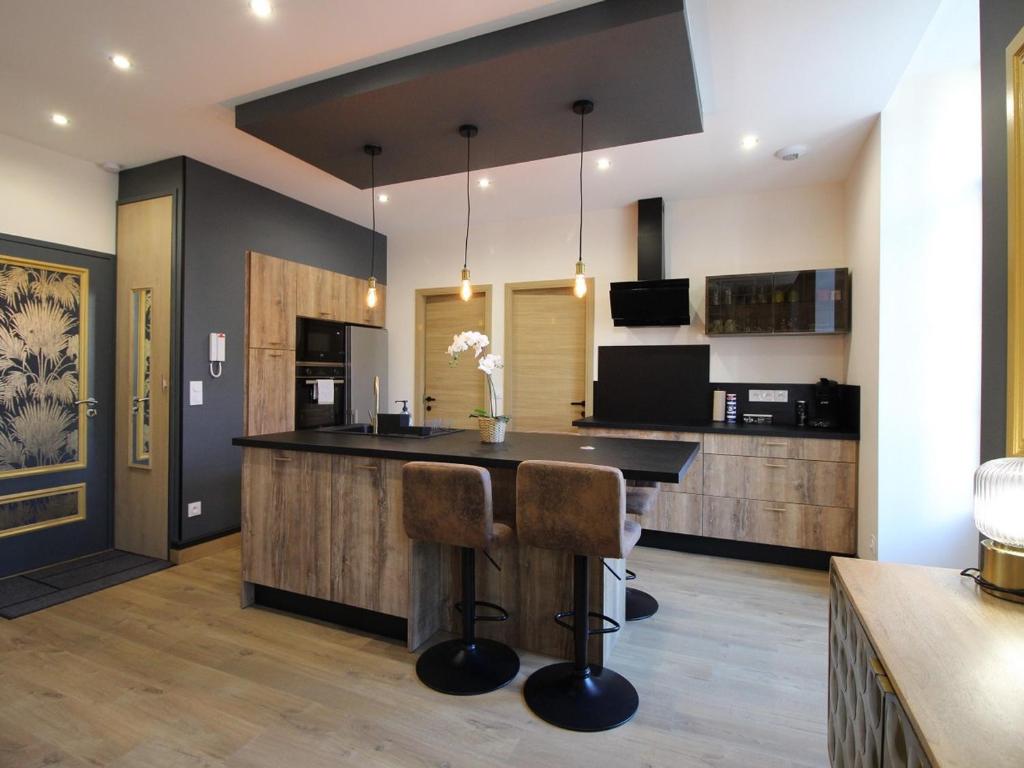 a kitchen with a bar with two stools at Appart rénové T2 bis, centre La Bourboule, WiFi, proche thermes - FR-1-608-277 in La Bourboule