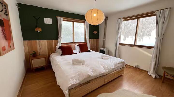 a bedroom with a large white bed with red pillows at Baan Yuki Niseko in Niseko