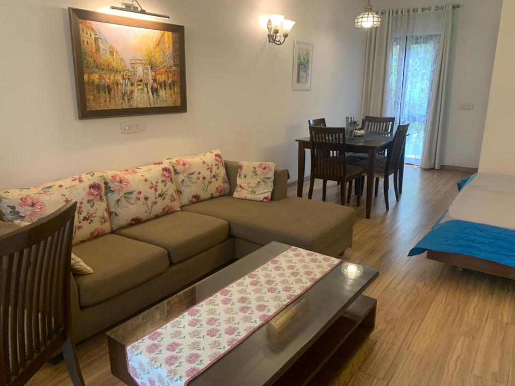 ein Wohnzimmer mit Sofa und Tisch in der Unterkunft STUDIO APARTMENT - TARUDHAN VALLEY GOLF RESORT Gurgaon in Gurgaon