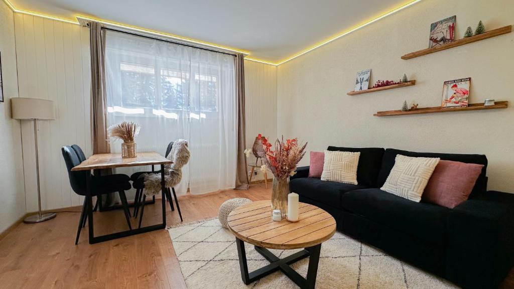 克莱恩 蒙塔纳Grand studio au cœur de Crans et au pied des pistes的客厅里有一张黑色沙发和一张桌子