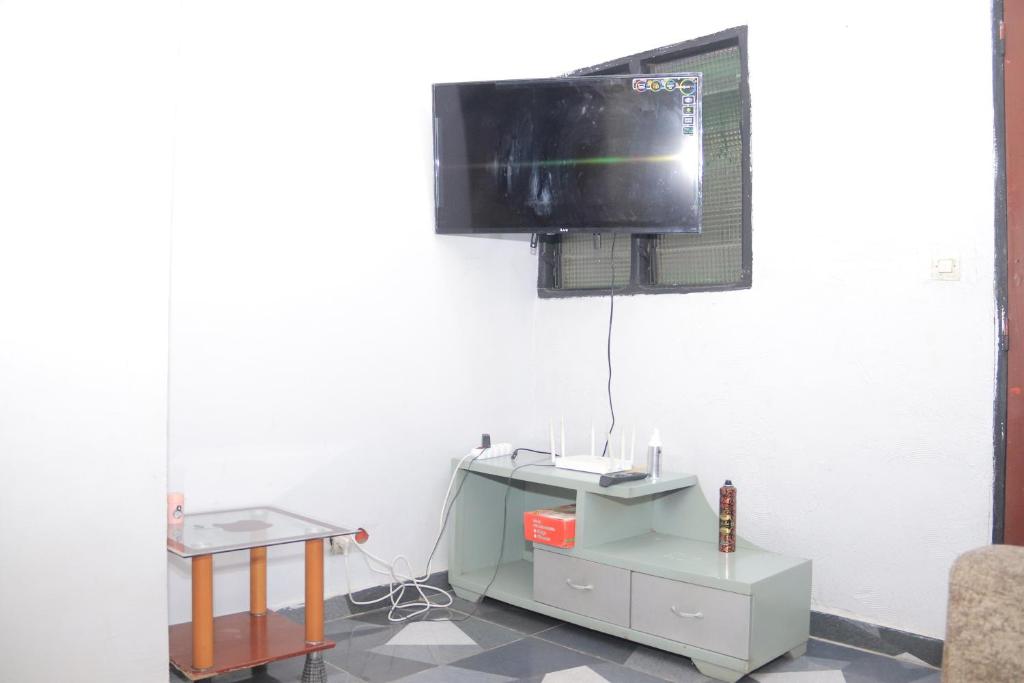 een kamer met een tv aan de muur en een tafel bij Afrika Nomades in Abidjan