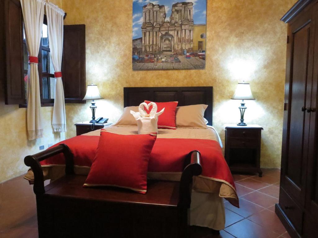 1 dormitorio con 1 cama grande con almohadas rojas en Casa Buena Vista, en Antigua Guatemala