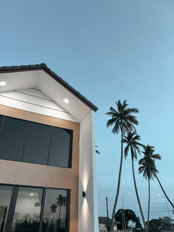a building with two palm trees in the background at Eastcape by The White Sands Homestay in Pekan