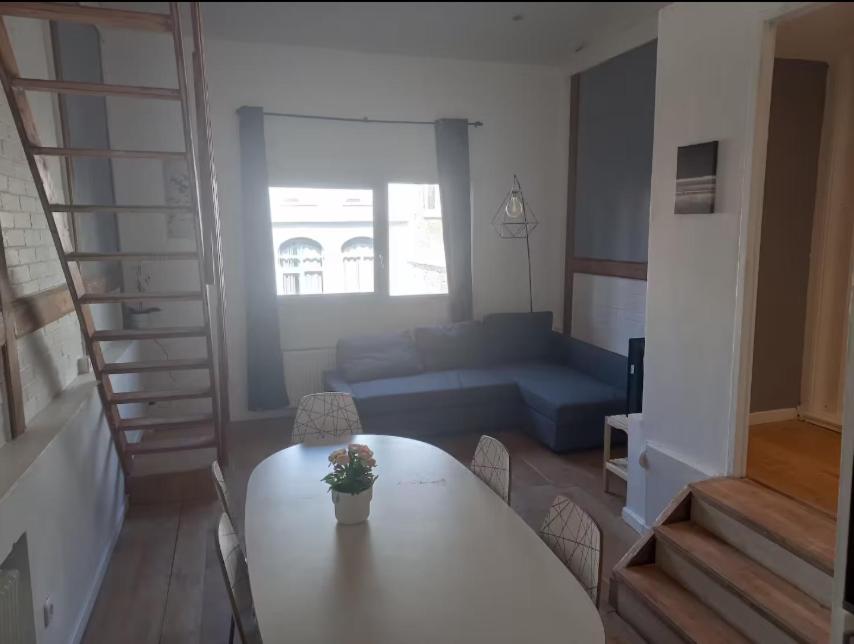 un salon avec une table et un canapé bleu dans l'établissement Joli T3 no4 Motte Parking, à Tourcoing