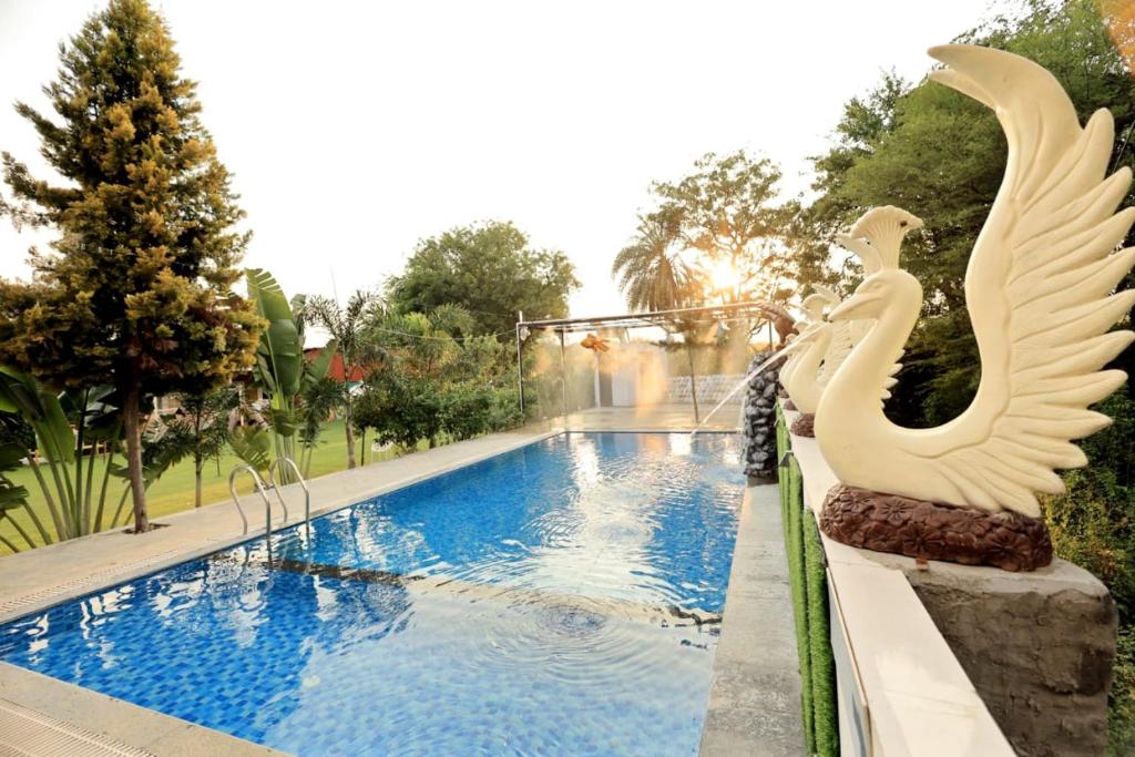 a swimming pool with a white bird statue next to it at Darshan Villa in Thūr
