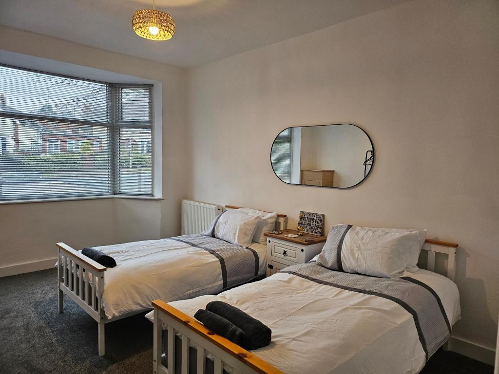 a bedroom with two beds and a mirror at The White Bungalow in Boughton
