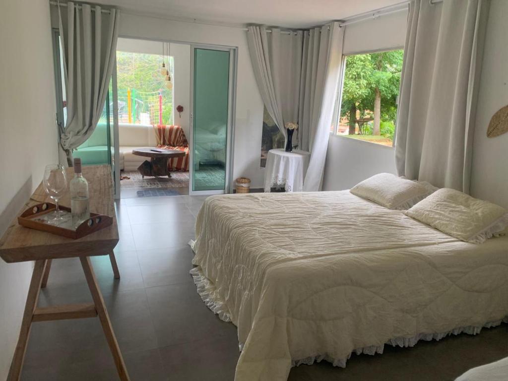 a bedroom with a bed and a table and a window at Sítio Recanto dos Lagos piscina sauna e churrasqueira in Marechal Floriano