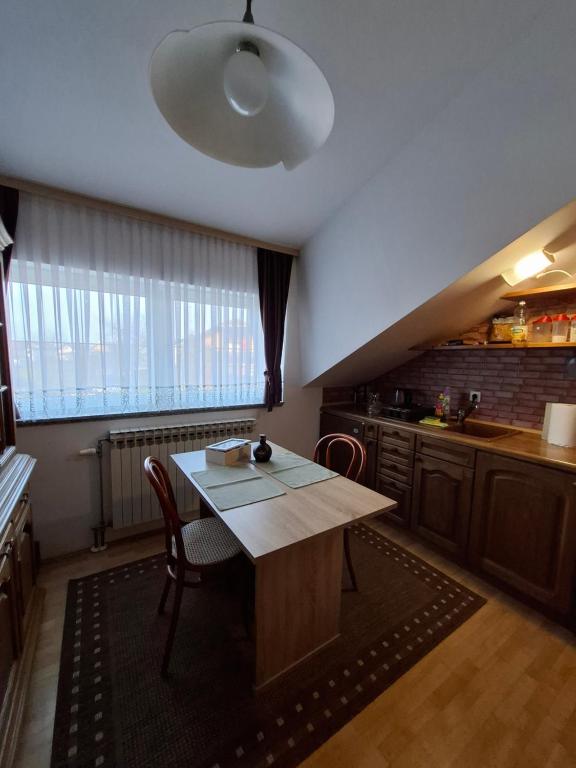 a kitchen with a wooden table and a large window at Apartman Anita in Varaždin