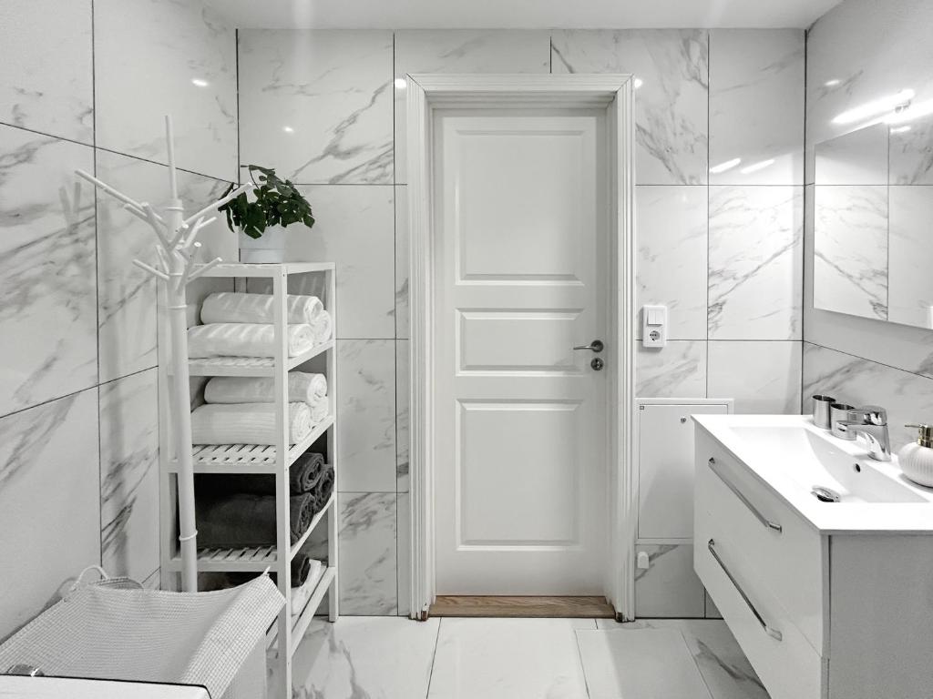 a white bathroom with a sink and a towel rack at Lyxig Stadsro och Utrymme villa i Malmö in Malmö