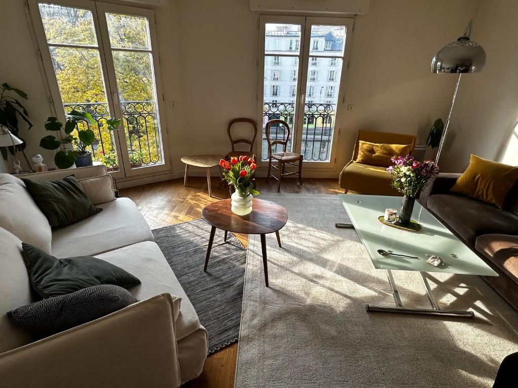 un salon avec un canapé et une table avec des fleurs dans l'établissement Appartement spacieux et lumineux - Canal Saint Martin, à Paris