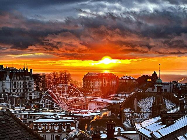 a sunset over a city with a ferris wheel at Studio charmant centré à Lausanne in Lausanne