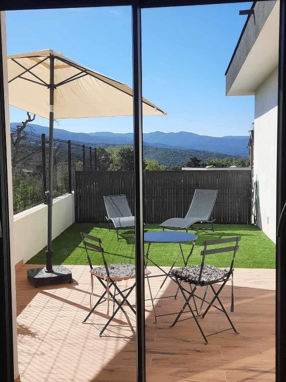 un patio avec une table, des chaises et un parasol dans l'établissement Studio neuf porticcio, à Porticcio