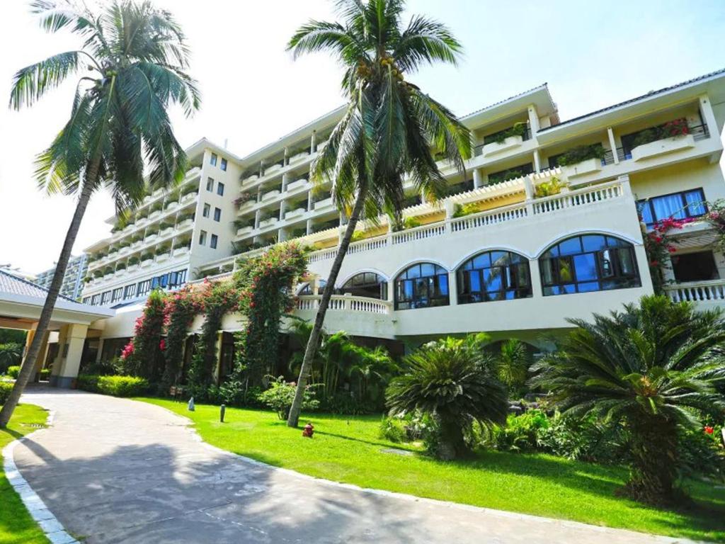 un gran edificio blanco con palmeras delante en Palm Beach Resort & Spa, en Sanya