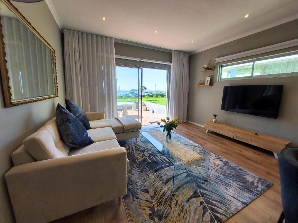 a living room with a couch and a flat screen tv at Mouille Point Seafront Cottage in Cape Town