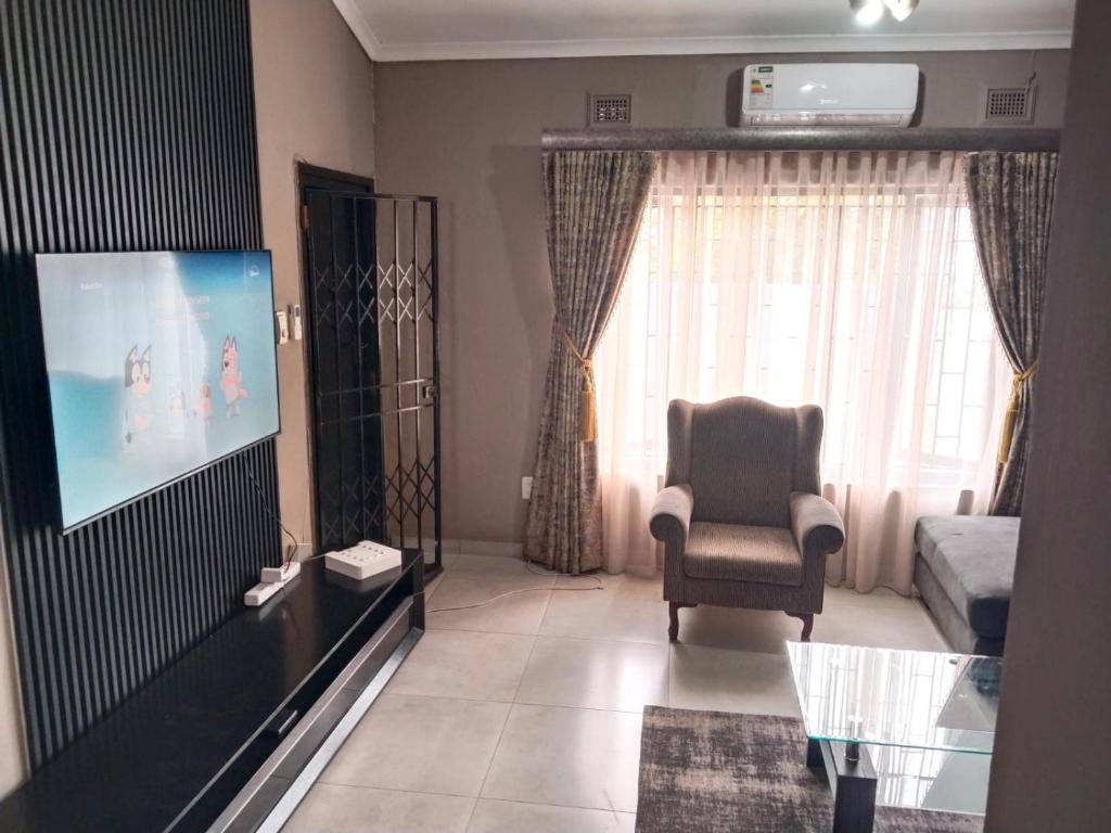 a living room with a chair and a flat screen tv at Pistachio villa in Durban