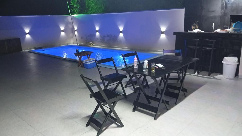 a table and chairs in front of a swimming pool at Casa de férias Branvek in Brusque
