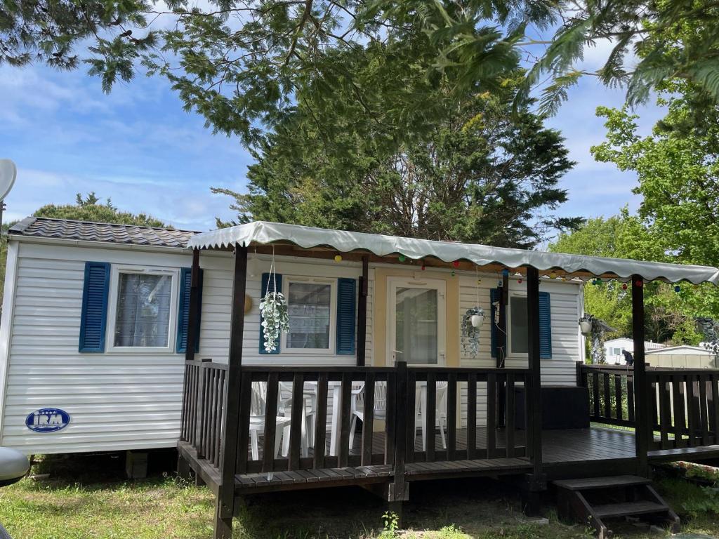 a tiny house with a porch and a deck at Mobilhome Super Titania - 3 Bedrooms - Family Camping JF102 in Les Mathes