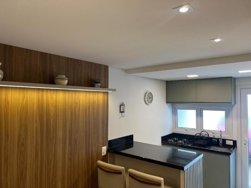 eine Küche mit einer Theke und einer Holzwand in der Unterkunft MRG - Convidativa Casa 3D em Condomínio Privativo em Canela - Próximo ao Parque Terra Mágica Florybal in Canela