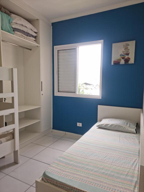 um quarto azul com uma cama e uma janela em Doce Vida Ubatuba - Próximo as Praias, Centro e Restaurantes em Ubatuba
