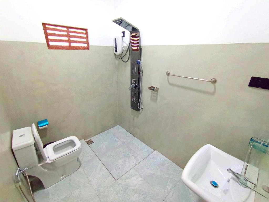 une salle de bain avec des toilettes blanches et un lavabo dans l'établissement Abi Inn, à Mirissa