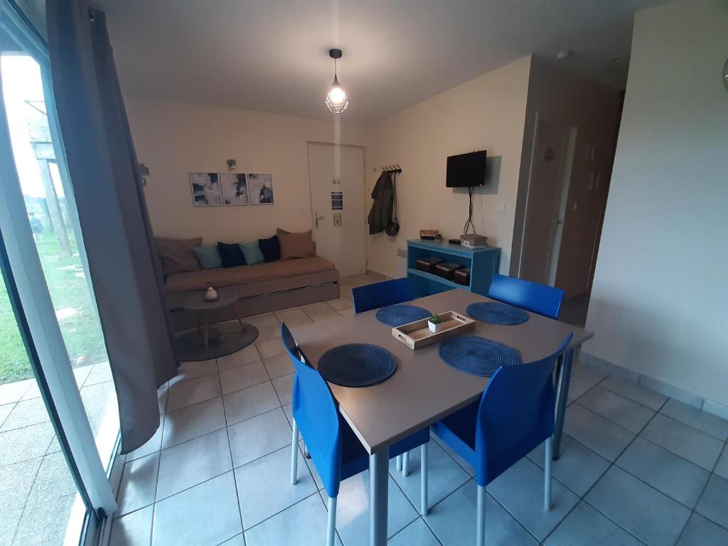 a dining room with a table and blue chairs at Quartier des peintres - Poussin in Chaveignes