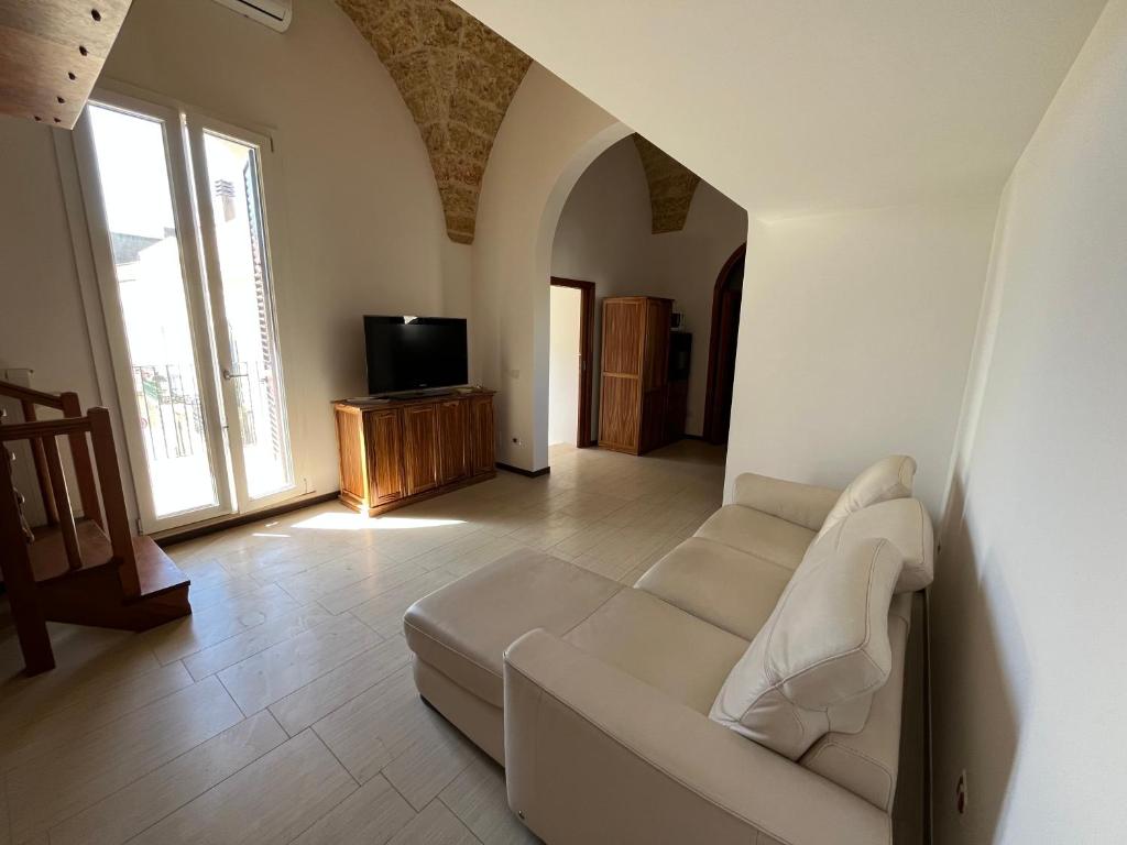 a living room with a white couch and a television at La casa della nonna - Guesthouse in Castrignano del Capo