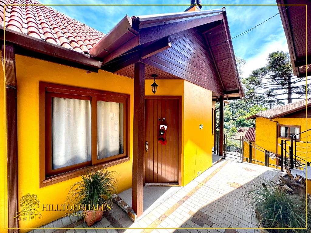 a yellow house with a brown door and windows at Hilltop Chalés Gramado in Gramado