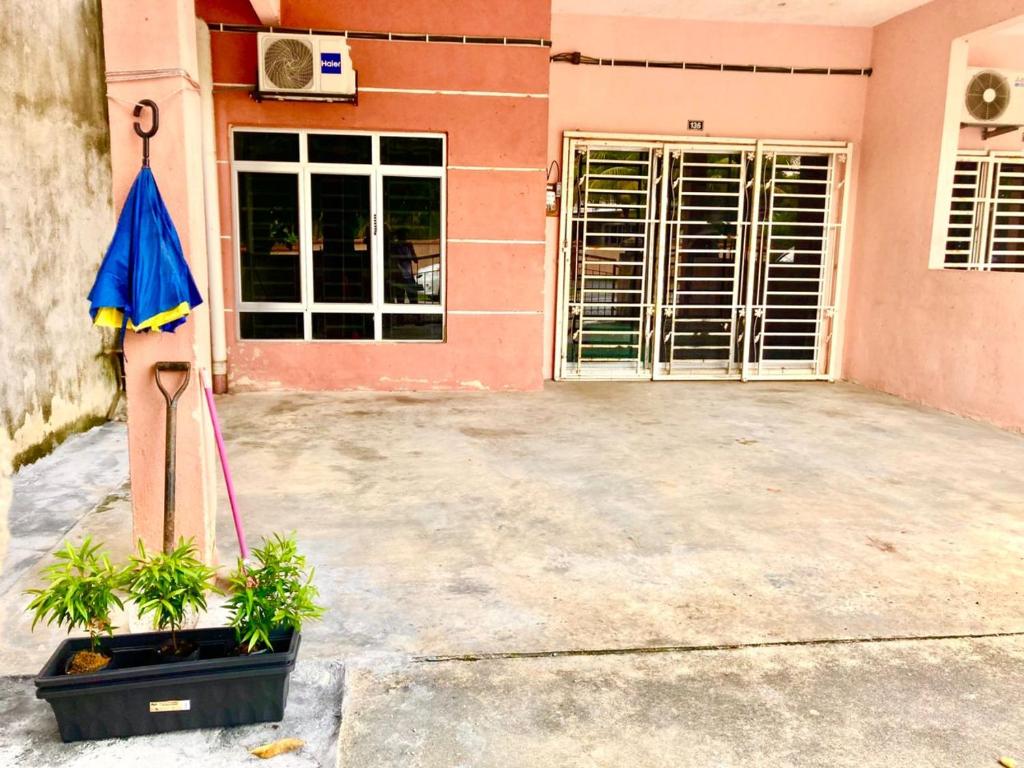 una casa con un ombrello e piante davanti di Isyfaq Homestay Seremban Rahang 3 Bedrooms a Seremban